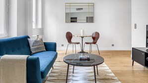 A modern living room with a blue sofa, a round coffee table, and a dining table with two chairs. - Blueground | Latin Quarter, nr Sorbonne (Paris)