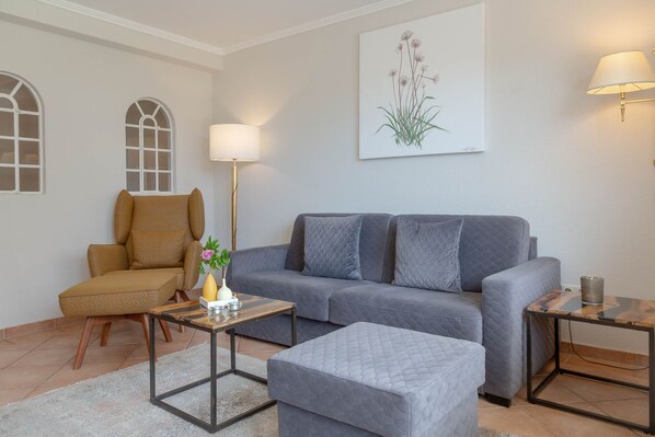 A living room with a grey sofa, a brown armchair, a small coffee table, and a floor lamp.