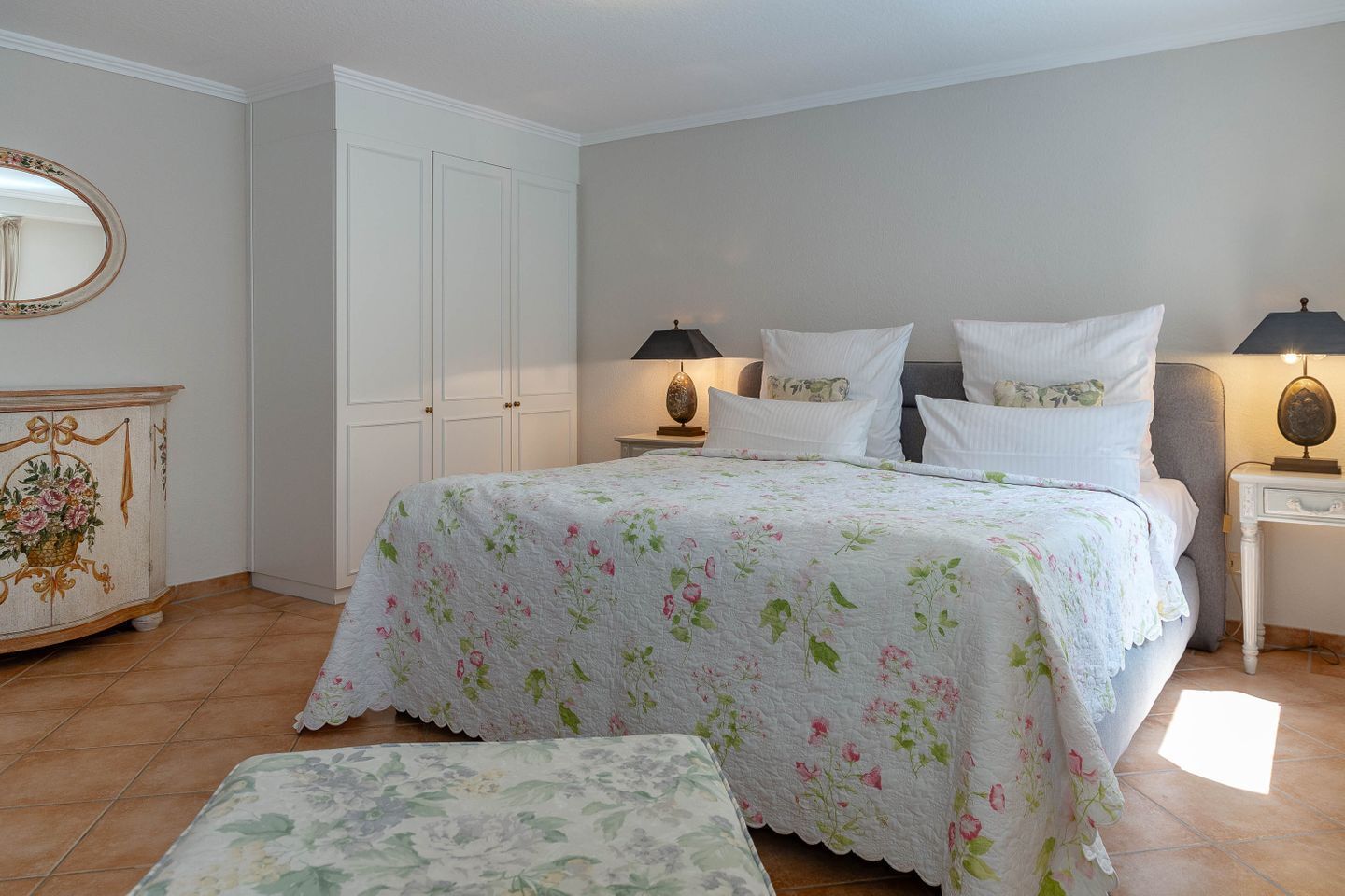 A bedroom with a bed, two bedside tables, a nightstand, a dresser, and a mirror.