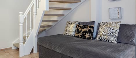 A modern living room with a grey sofa set, a white staircase, and two wall art pieces.