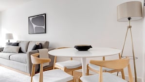 Una sala de estar moderna con un sofá gris, una mesa redonda blanca y una lámpara de pie.
