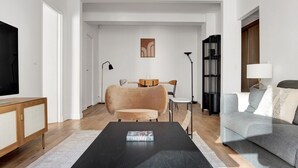 Un salon moderne avec un canapé, une table basse, un téléviseur et une bibliothèque.