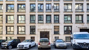 Un immeuble à plusieurs étages, avec une rangée de voitures garées devant.