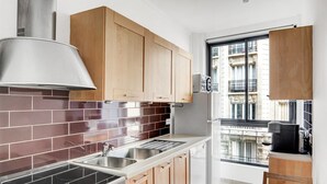 Une cuisine moderne dotée d’une hotte en acier inoxydable, de meubles en bois, d’un évier double et offrant une vue sur la ville grâce à une grande fenêtre.