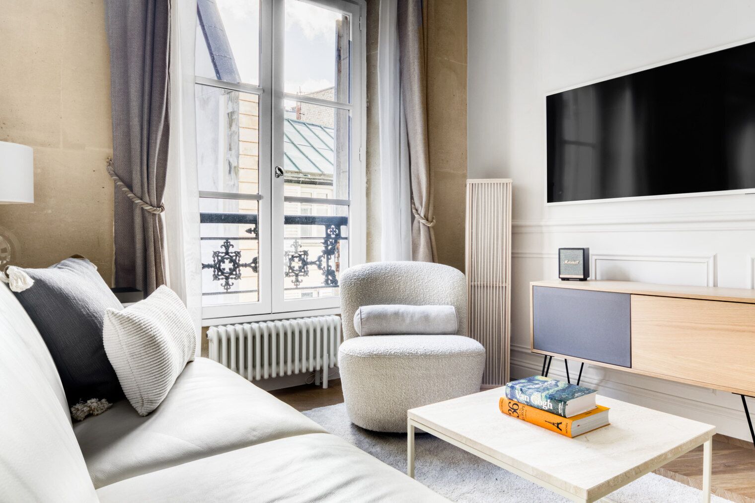Un salon moderne avec un canapé, un fauteuil et une table basse sur laquelle sont posés des livres.