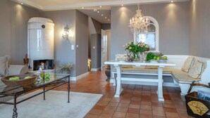 A spacious living room with a fireplace, a dining area with a white table and bench, and a chandelier. - Sönshörn 20 - Holiday apartment "Sönshörn 20" in Munkmarsch (Munkmarsch)