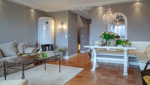 A living room with a fireplace, a dining table with a bench, and a chandelier. - Sönshörn 20 - Holiday apartment "Sönshörn 20" in Munkmarsch (Munkmarsch)