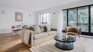 A modern living room with a sofa, a coffee table, and a dining area. - Blueground | Porte Maillot. balcony & concierge (Paris)