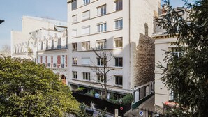 A multi-story building with a modern facade, large windows, and a visible entrance with a metal gate. - Blueground | Porte Maillot. balcony & concierge (Paris)
