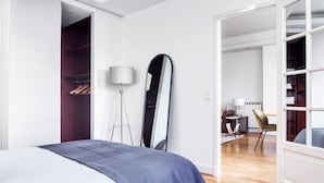 Un dormitorio moderno con una cama grande, una lámpara de pie, un espejo y un armario.