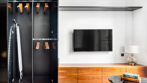 Una sala de estar moderna con un armario negro, un televisor de pantalla plana, un mueble de madera y una mesa de centro de vidrio con libros.