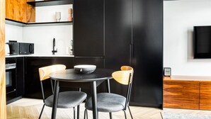 Una cocina moderna con armarios negros, una mesa redonda de comedor y dos sillas.