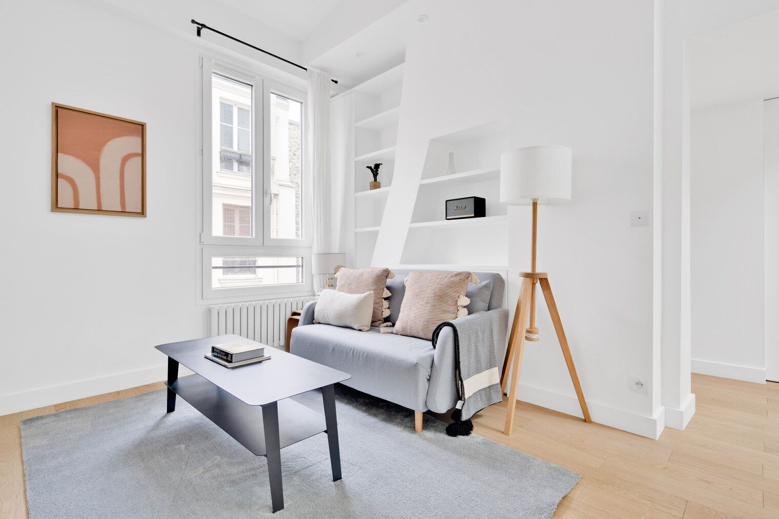 Een moderne woonkamer met een grijze bank, een bijzettafeltje en een vloerlamp.