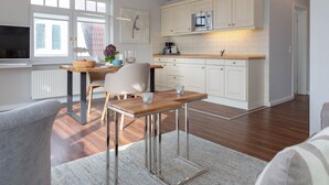 Eine moderne Küche mit weißen Schränken, einer Edelstahl-Mikrowelle und einem Holztisch.