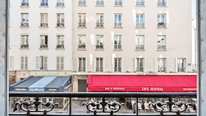 Un edificio con varias ventanas y balcones, un toldo rojo con la inscripción 'CAFE CENTRAL' y un letrero que dice 'DAI'S HOUSE' sobre una fachada comercial.