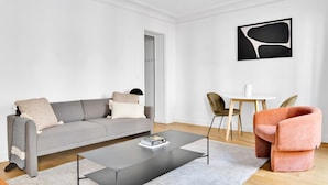 Una sala moderna con un sofá gris, una mesa de centro y un sillón rosa.