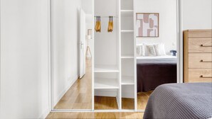 A modern bedroom with a bed, a dresser, and a walk-in closet with hanging space. - Blueground | Michel-Ange Molitor, near tennis (Paris)