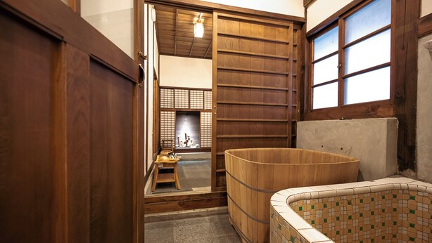 A traditional Japanese room with tatami flooring, a wooden barrel, and a tiled bathtub.