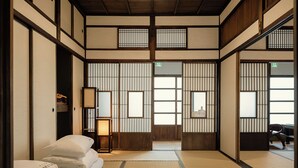 A traditional Japanese room with tatami flooring, shoji screens, and a futon bed.