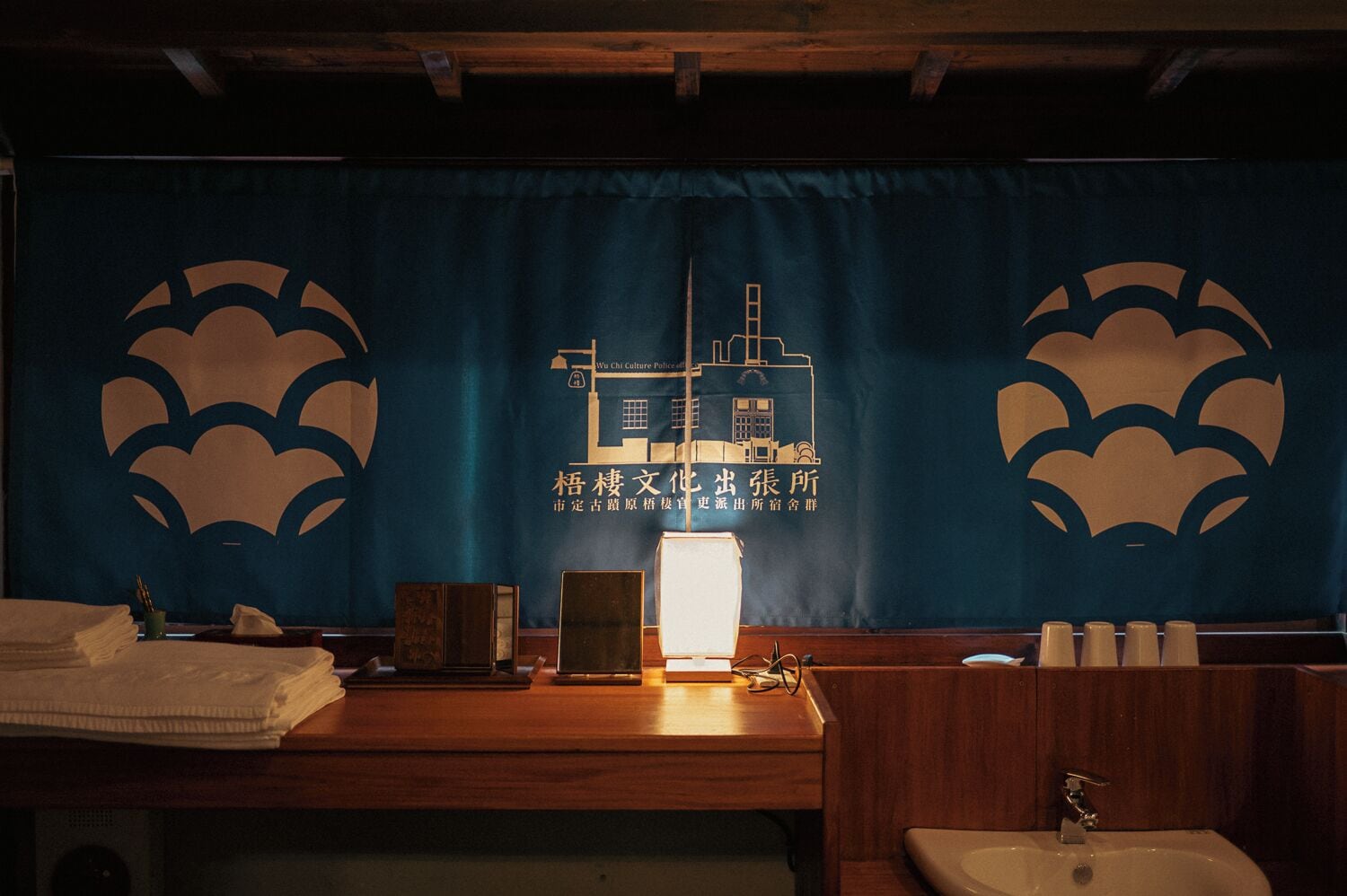 A traditional Japanese-style bathroom with a wooden counter, a sink, and a towel rack.