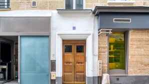 A building with a wooden door, a glass door, and a window with a view of a shop. - Blueground | Louvre, nr Rue Rivoli shops (Paris)