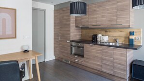 A modern kitchen with wooden cabinetry, a black countertop, and stainless steel appliances.