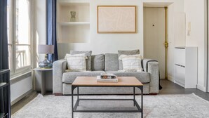 A living room with a grey sofa, a coffee table, a lamp, and a framed abstract artwork on the wall.