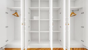Un dressing blanc, de bonne taille, avec de nombreuses étagères et un espace pour suspendre les vêtements.