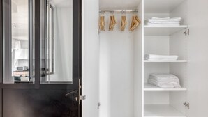 A modern bathroom with a dark door, a glass shower enclosure, and a white shelving unit with folded towels. - Blueground | Le Marais, renovated, furnished (Paris)