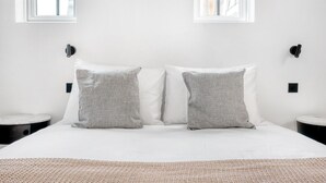 A bedroom with a large bed, two pillows, two bedside tables, and two windows. - Blueground | Le Marais, renovated, furnished (Paris)