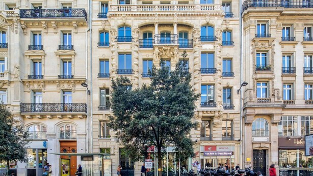 A multi-story building with ornate architectural details, a tree in front, and parked motorcycles on the sidewalk. - Blueground | Le Marais, furnished & equipped (Paris)