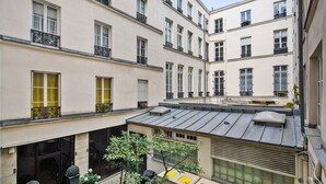 A courtyard with multiple buildings, balconies, and a small tree. - Blueground | Le Marais, elev, nr rue de Bretagne (Paris)