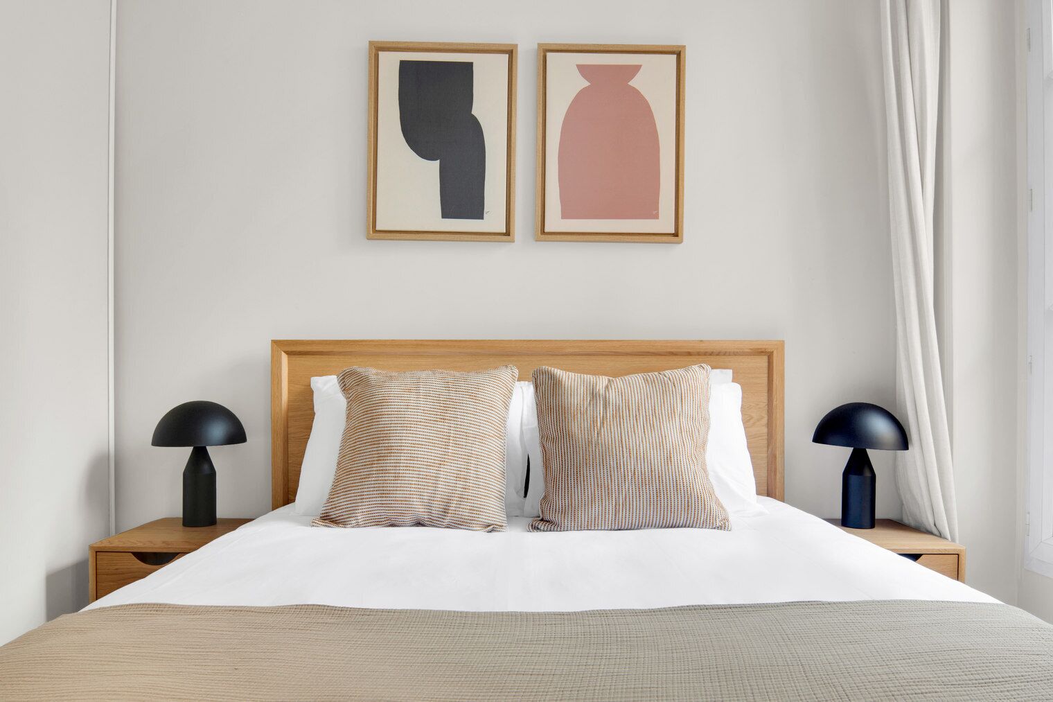 A neatly made bed with two pillows, a wooden headboard, and two bedside lamps.