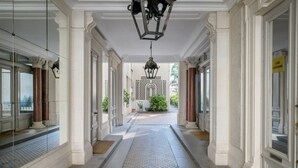 A corridor with white columns, a patterned floor, and a hanging lantern. - Blueground | Monceau, furnished, near park (Paris)