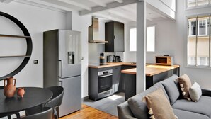 A modern kitchen with a built-in oven, a refrigerator, and a microwave. - Blueground | Monceau, furnished, near park (Paris)