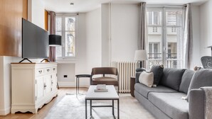 Een moderne woonkamer met een bank, fauteuil, televisie en een witte kast.