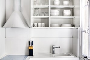 A modern kitchen with white cabinetry, a stainless steel sink, and a built-in oven.