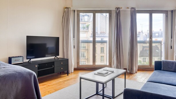 A modern living room with a flat-screen TV, a small table, and a sofa. - Blueground | Argentine, elevator, nr Porte Maillot (Paris)