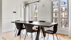 Un coin repas avec une table rectangulaire, six chaises et un saladier posé sur la table.