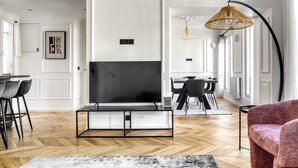 Un salon moderne doté d’un grand téléviseur à écran plat, d’une cheminée et d’un coin repas avec une table et des chaises.