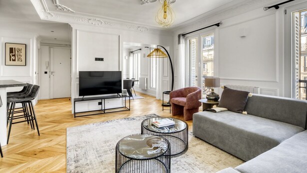 Un salon moderne avec un canapé gris, un téléviseur et une table basse.