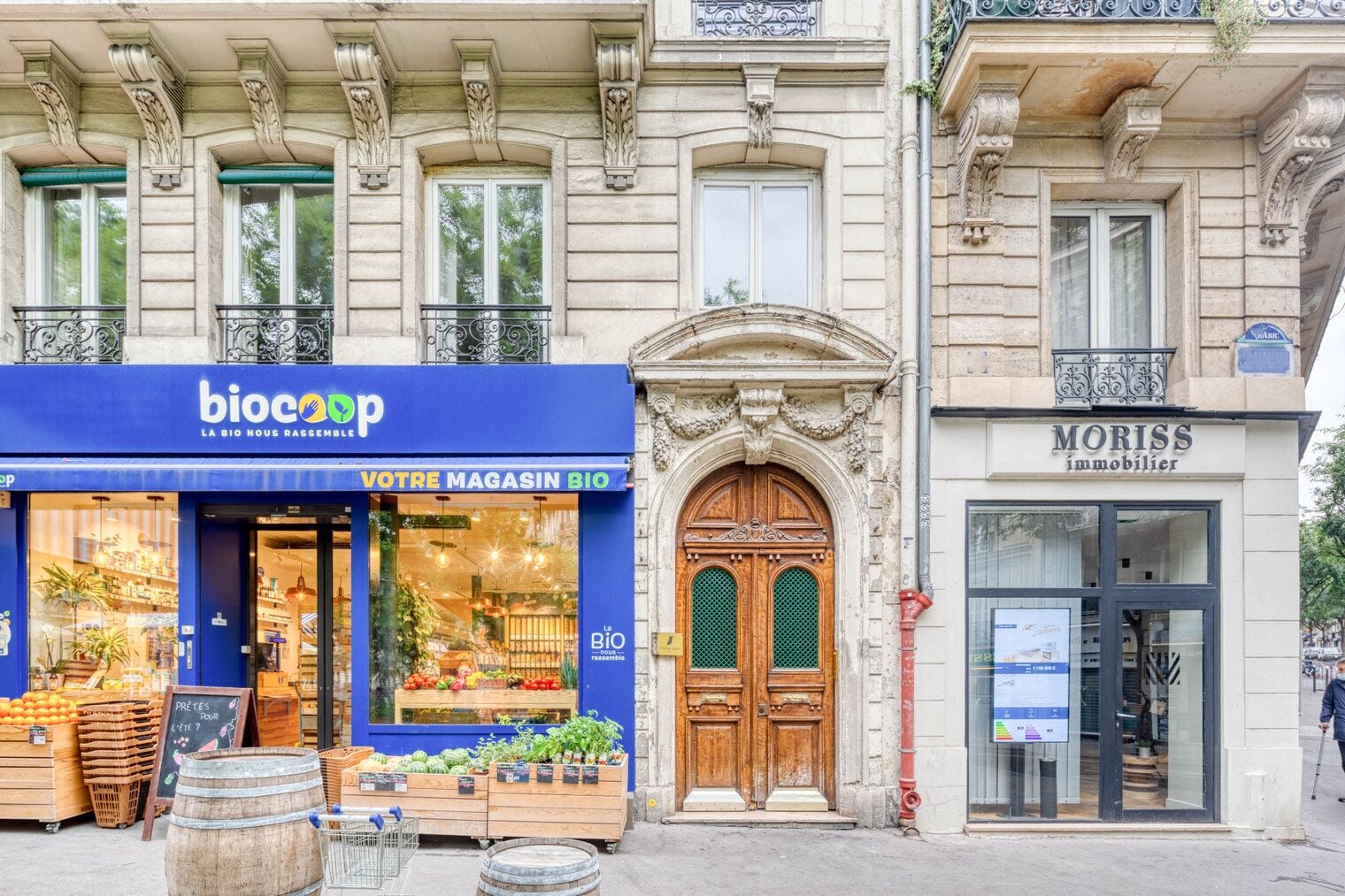 A storefront with a blue awning labeled "biocop" and a wooden door with a green window.