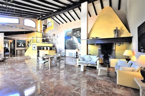 Amplia sala de estar con chimenea, comedor y escalera que conduce a un nivel superior.
