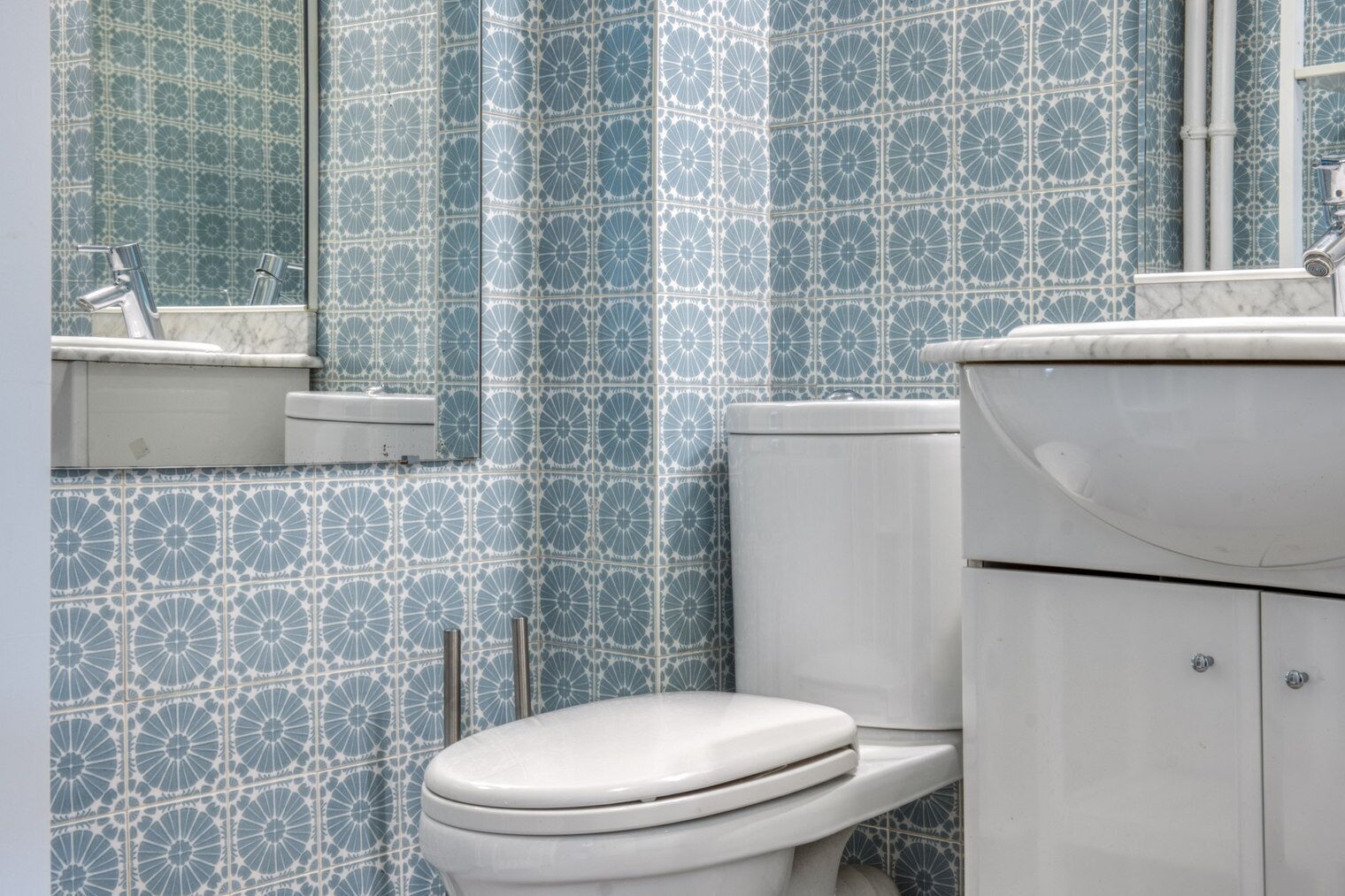 Een badkamer met toilet, wastafel en spiegel.