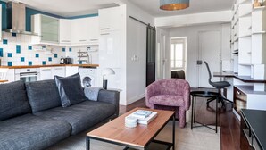A modern apartment with a grey sofa, a wooden coffee table, a pink armchair, and a desk with a chair. - Blueground | Sentier, furnished, nr Montorgueil St (Paris)