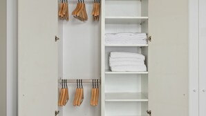 Une armoire blanche dotée de nombreuses étagères et de barres pour suspendre les vêtements, certaines comportant des serviettes pliées.