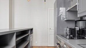 Une cuisine moderne avec des meubles de couleur grise, un plan de travail en bois et un four encastré.