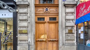 A wooden double door with a decorative upper section and a plaque above it. - Blueground | Le Marais, elevator, nr Rue Rambuteau (Paris)