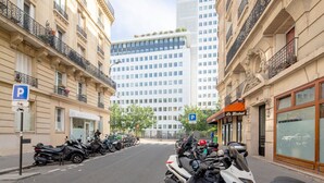 A street lined with parked motorcycles and bicycles, with buildings featuring classic European architecture and a restaurant named "Le Bistro" on the right. - Blueground | Bir Hakeim, nr Eiffel Tower (Paris)