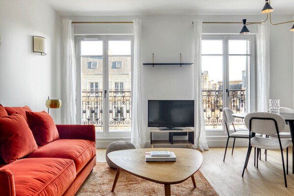 Relax in this stylish living room with a flat-screen TV, comfortable sofa, and dining area.